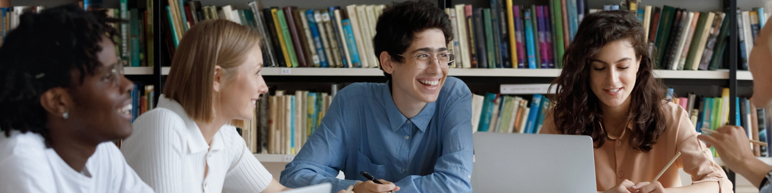 Inset_Grantees_2 Group of diverse high school students talking, sitting in a library